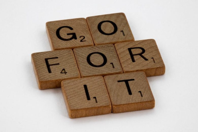 Close-up of Scrabble letters forming the phrase 'Go For It' on a white background.